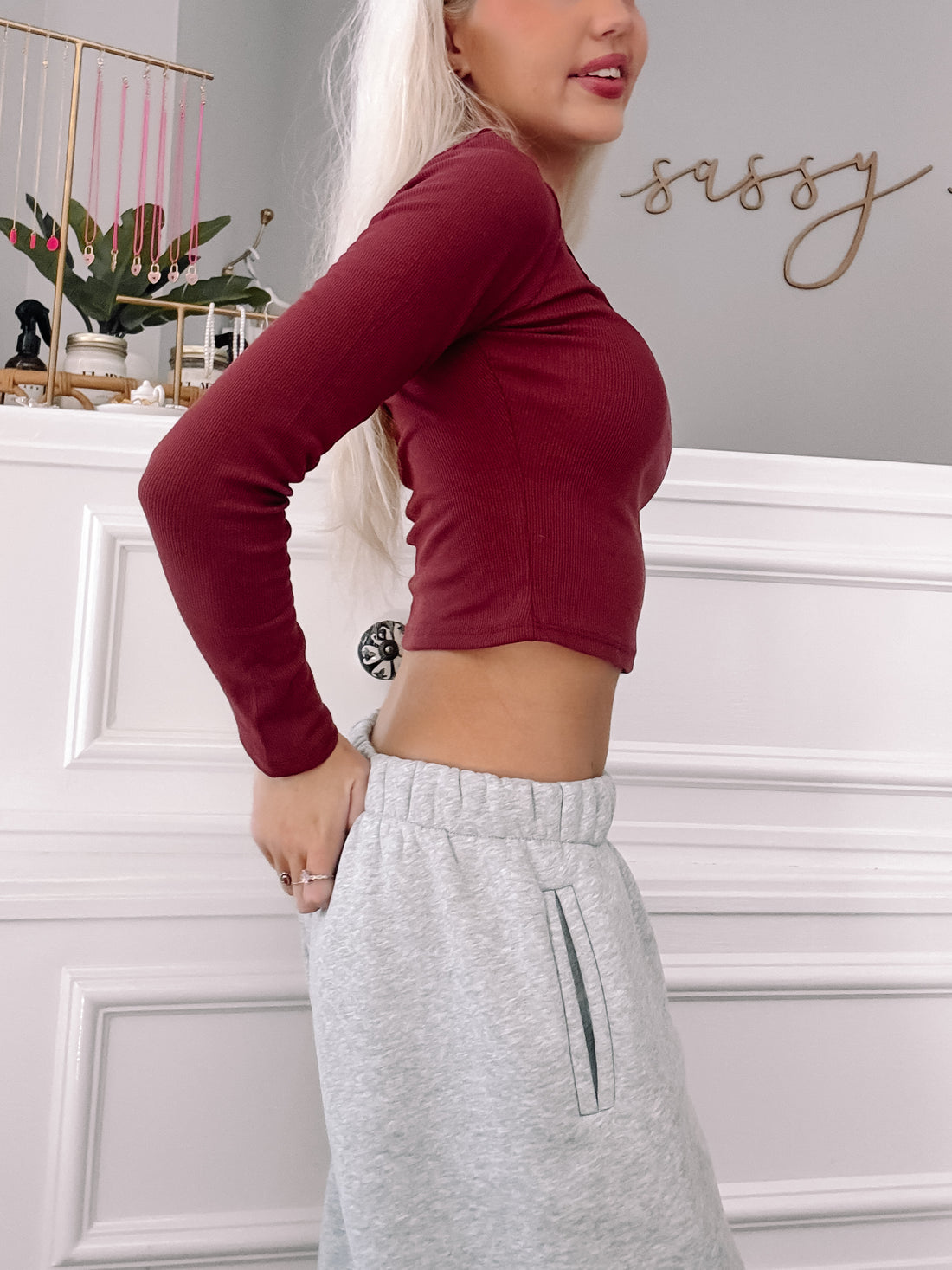 Burgundy long-sleeve fitted crop top worn against a white wall.
