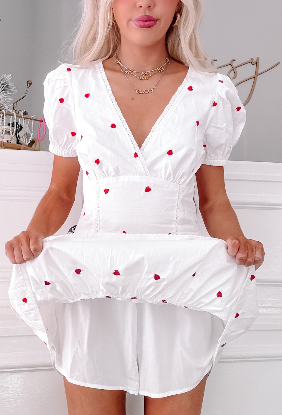 White mini dress with puff sleeves and scattered red heart embroidery; shown on model.
