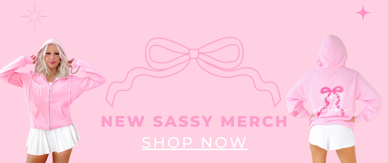 Sassy Merch Collection at Sassy Shortcake - Pink hoodie with bow design on a pink background with text New Sassy Merch Shop Now
