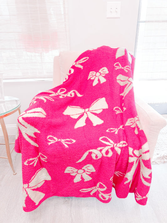 Hot pink Bow Blanket with cream bow pattern, cozy plush texture.
