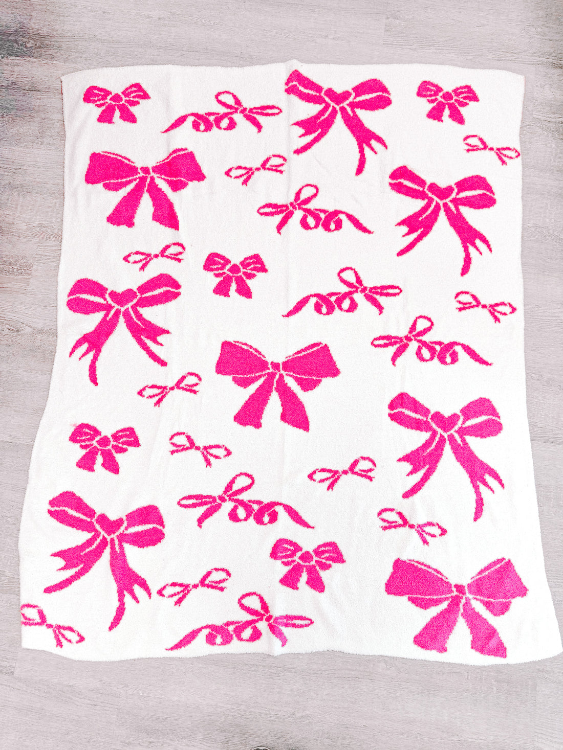 Soft white blanket featuring a pink bow pattern.
