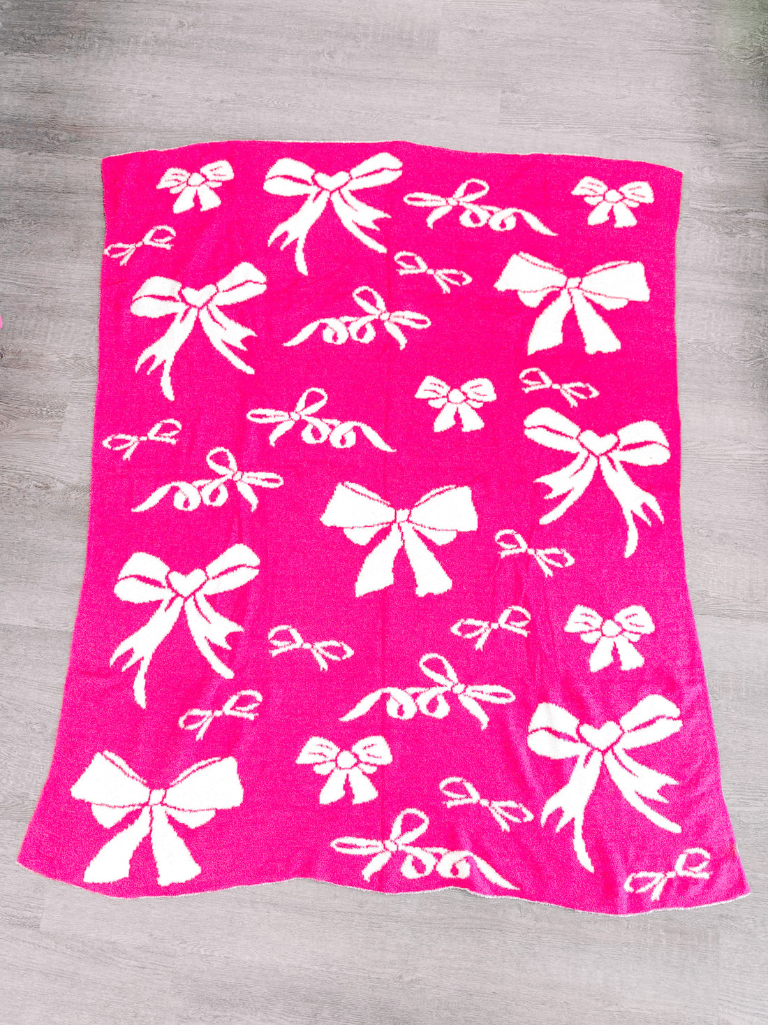 Hot pink knitted throw blanket adorned with a white bow pattern.
