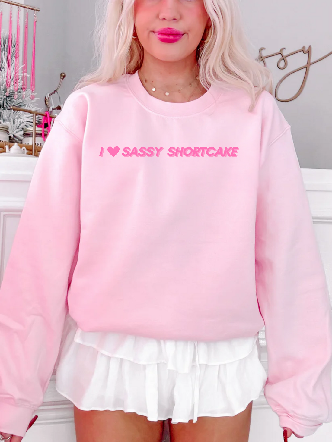 Cozy baby pink sweatshirt styled on model, featuring playful "I heart Sassy Shortcake" graphic.