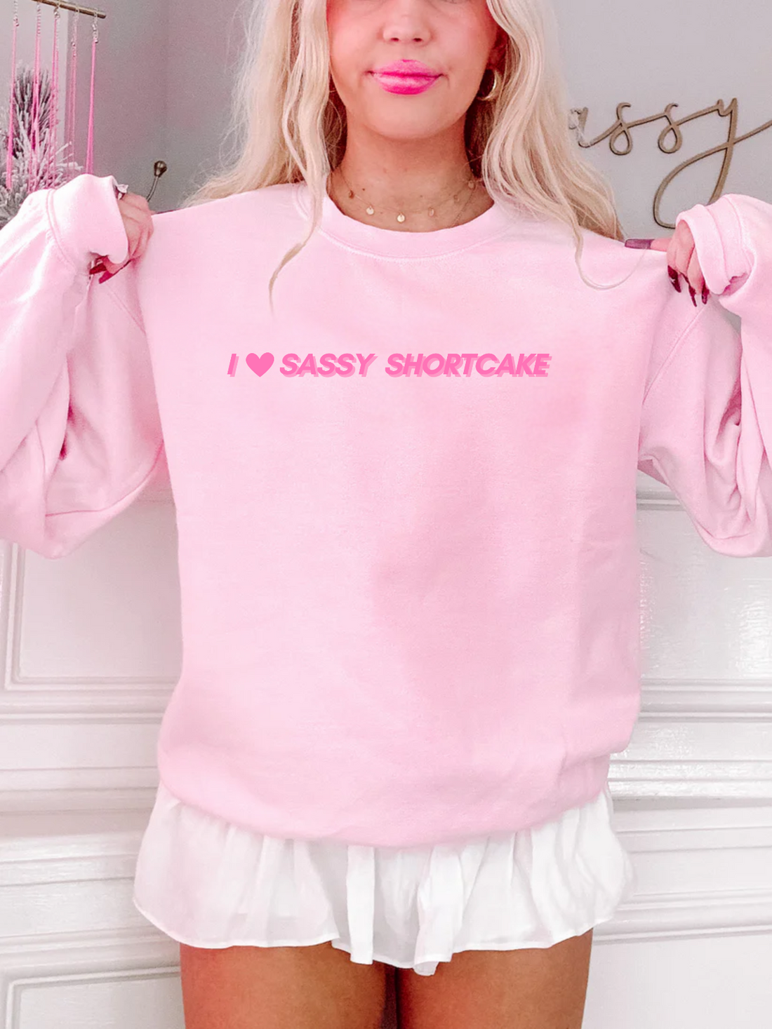Model wearing light pink crewneck with I heart Sassy Shortcake text. Sassy Shortcake Merch 