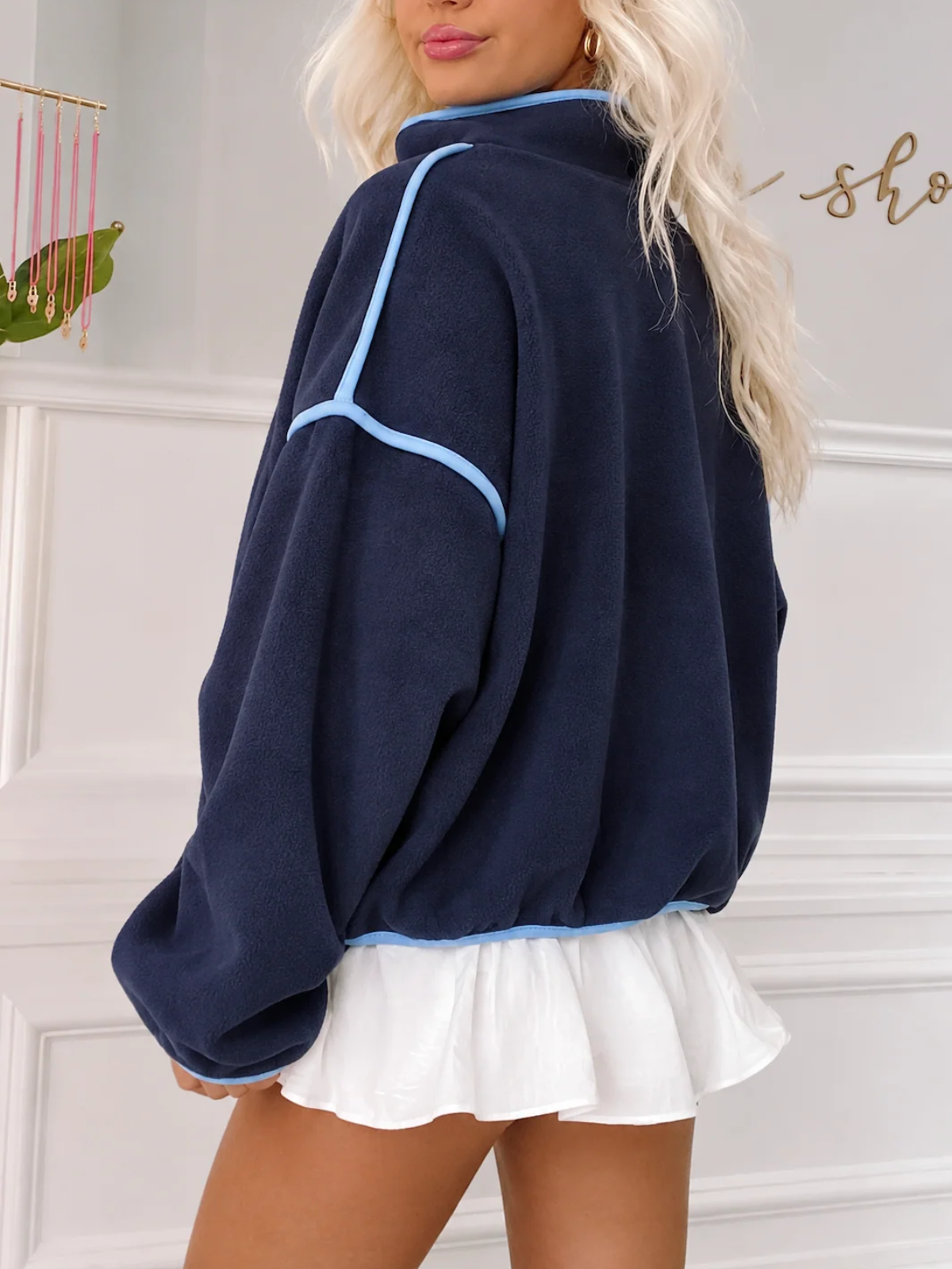 Close-up of the Sassy Shortcake Ivy League Pullover showing the navy fleece texture, light blue piping, and snap placket.
