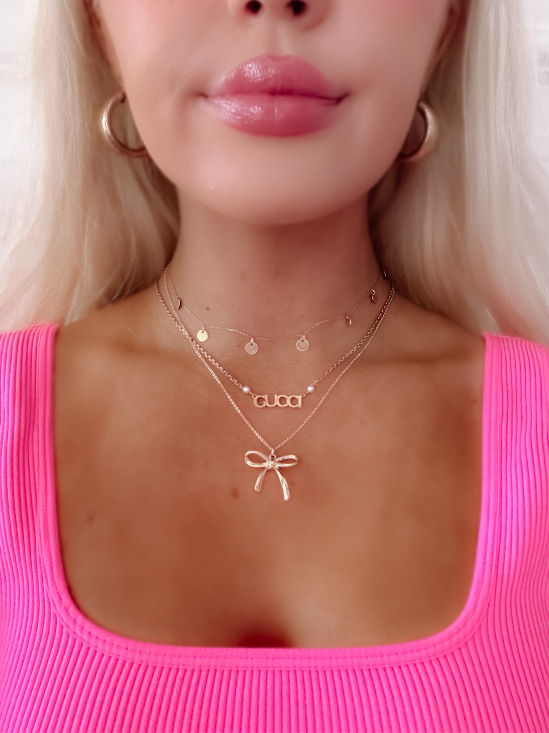 Gold Jordyn bow necklace layered with delicate chains and charms.
