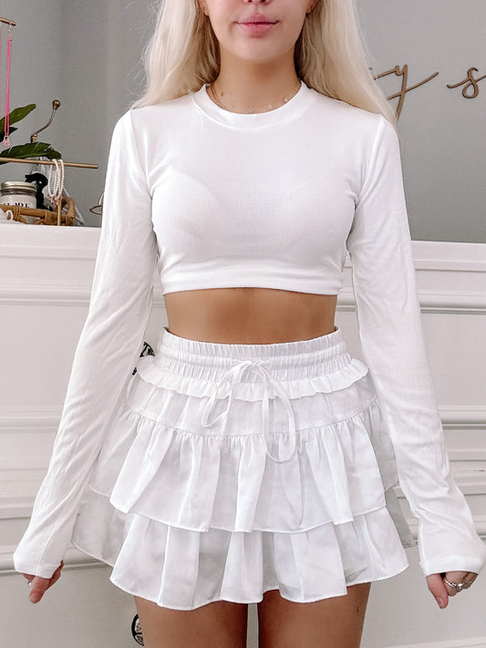 White ribbed long-sleeve crop top and layered ruffle mini skirt, styled together.