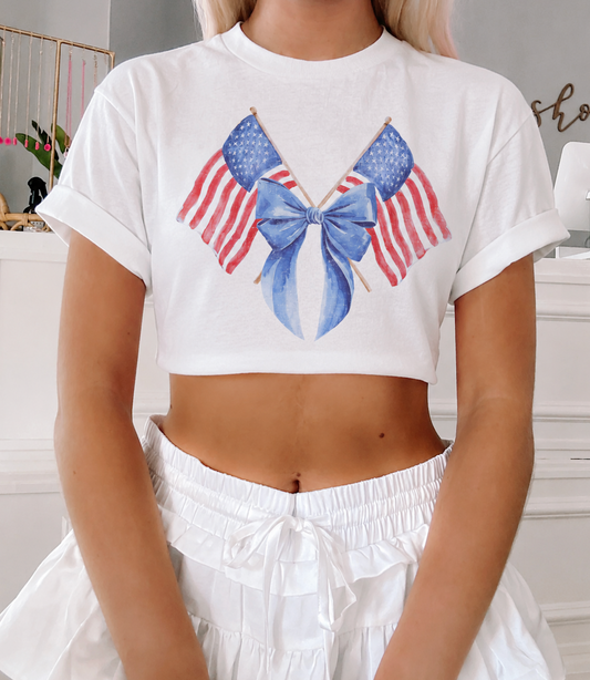 Close-up of the hand-painted watercolor flag and bow graphic on The Liberty Ribbon Tee by Sassy Shortcake