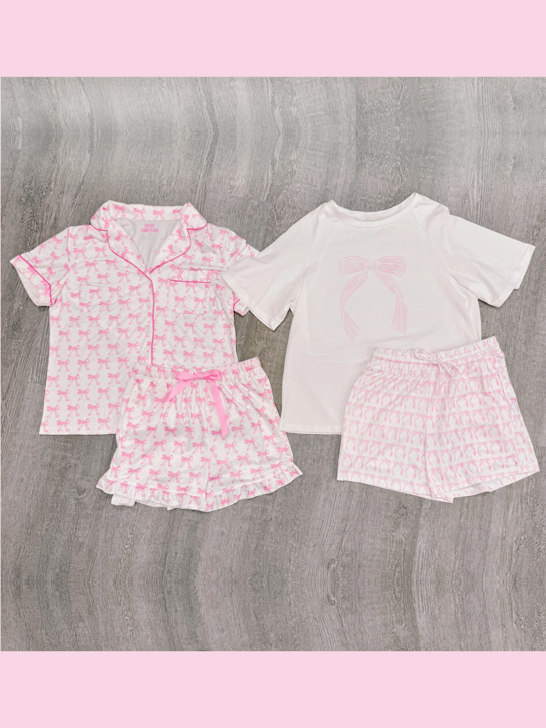 Pink and white children's sleep set featuring a bow print, shown on a gray wood background.
