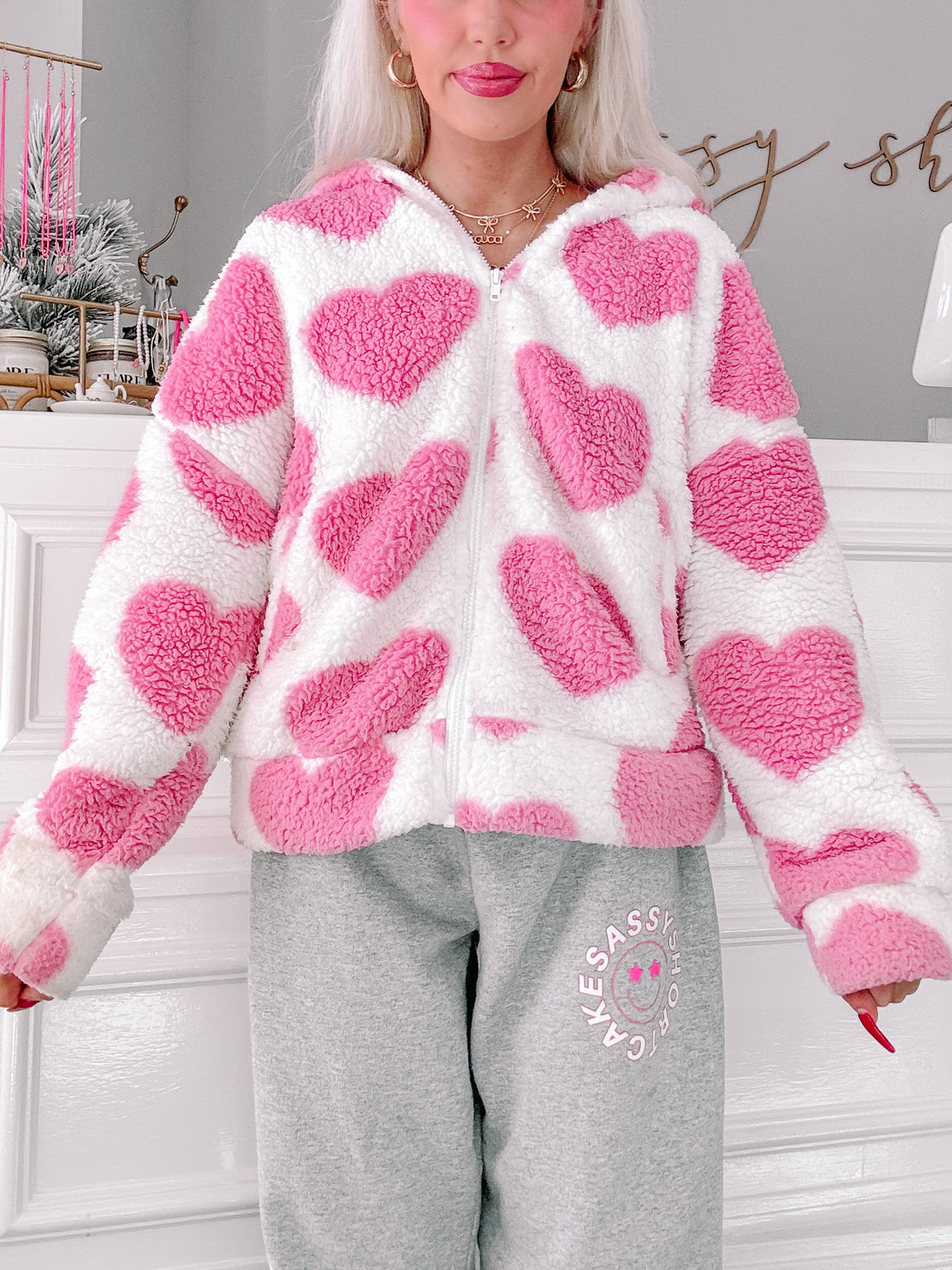 Pink heart-print sherpa jacket, cozy fleece fabric, full-zip closure.
