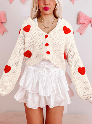 Ivory Love is in the Air Cardigan with red heart details.
