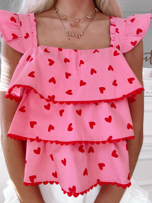 Pink tiered top with red hearts, scalloped trim