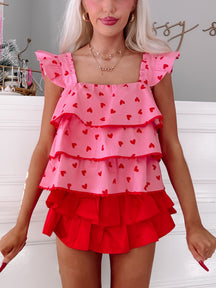 Pink tiered ruffle top with red hearts, layered over a red ruffled skirt.
