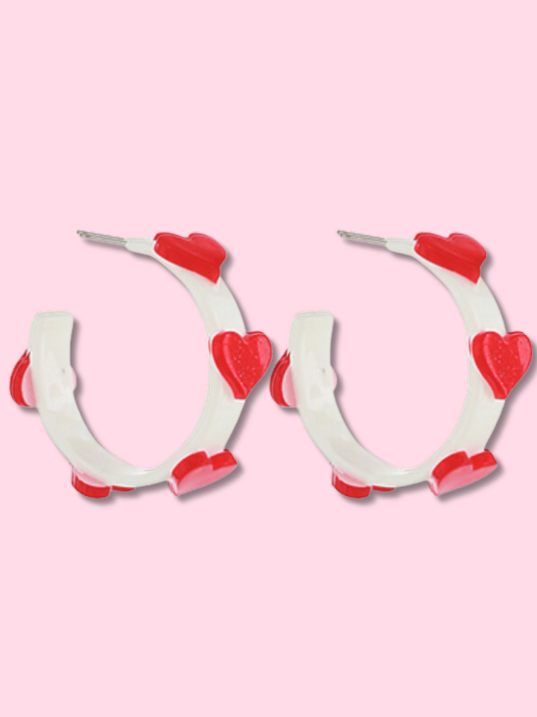 Red and white heart-shaped hoop earrings against a pink background.
