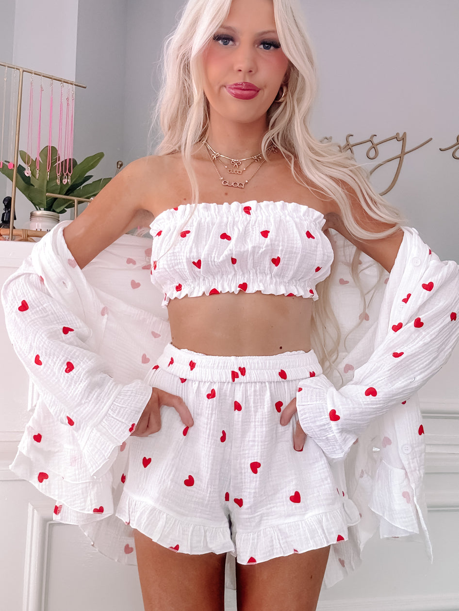 White heart-print lounge set: ruffled shorts and cropped top with matching open-front shirt.
