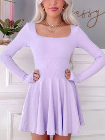Lilac tennis dress with long sleeves and skater skirt, showcased against a white wall from Sassy Shortcake
