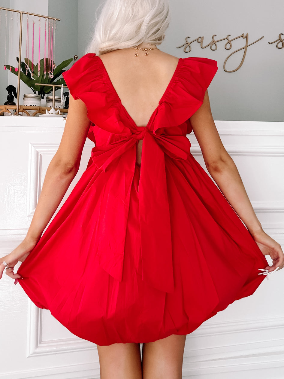 Red mini dress with ruffle sleeves and a bow tie back detail.
