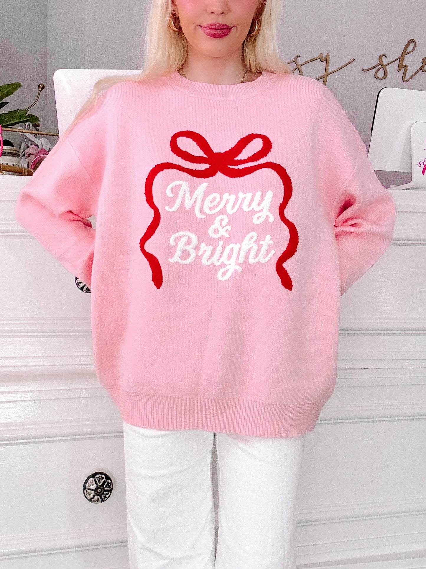 girl wearing a pink sweater with 'Merry & Bright' text and red bow design from sassy shortcake