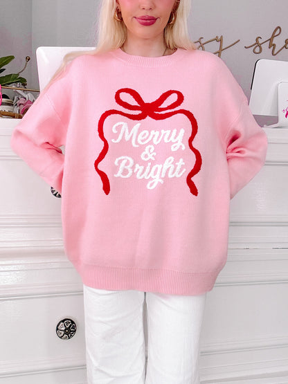 girl wearing a pink sweater with 'Merry & Bright' text and red bow design from sassy shortcake