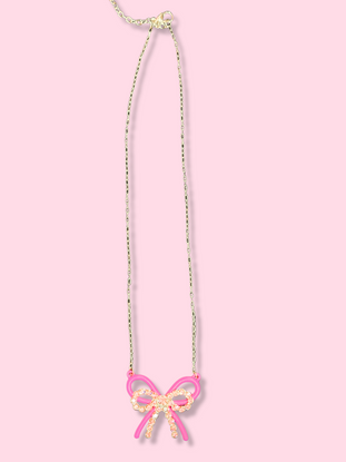 Pink bow necklace with gold chain on pink background
