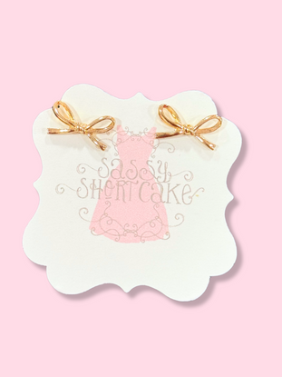 Gold Mini Ties Bow earrings on pink background
