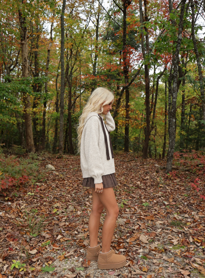 Sideview of the Mocha Ribbon Hoodie Sweater by Sassy Shortcake showing the knit hood, chocolate brown velvet ribbons, and ribbed hem.
