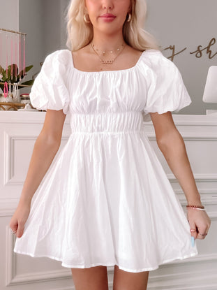 White puff-sleeve mini dress, cinched waist, perfect for summer.
