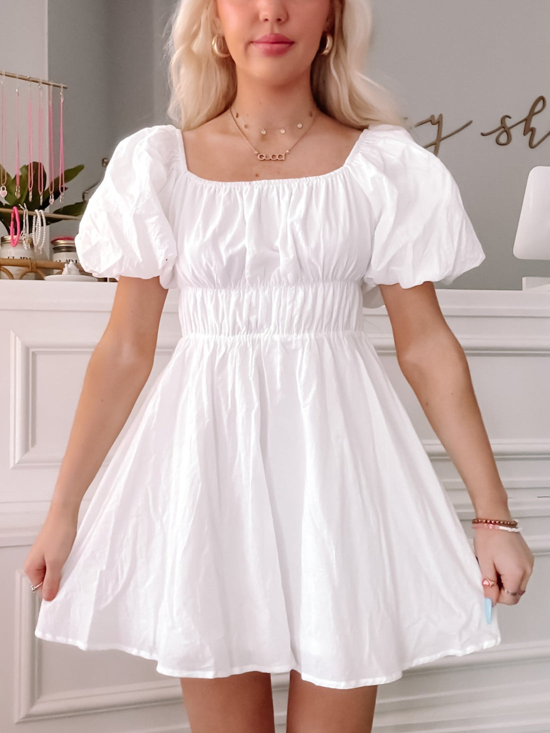 White puff-sleeve mini dress, cinched waist, perfect for summer.

