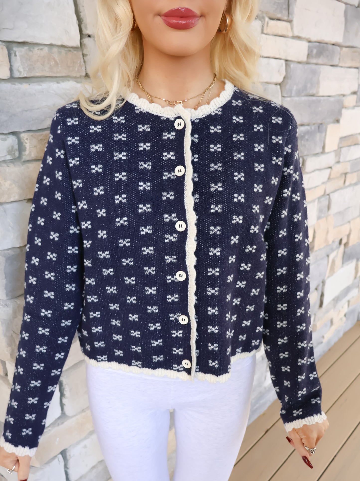 Close-up of the cozy navy cardigan knit with an x-pattern texture and detailed scalloped trim along the edges.