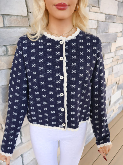 Close-up of the cozy navy cardigan knit with an x-pattern texture and detailed scalloped trim along the edges.