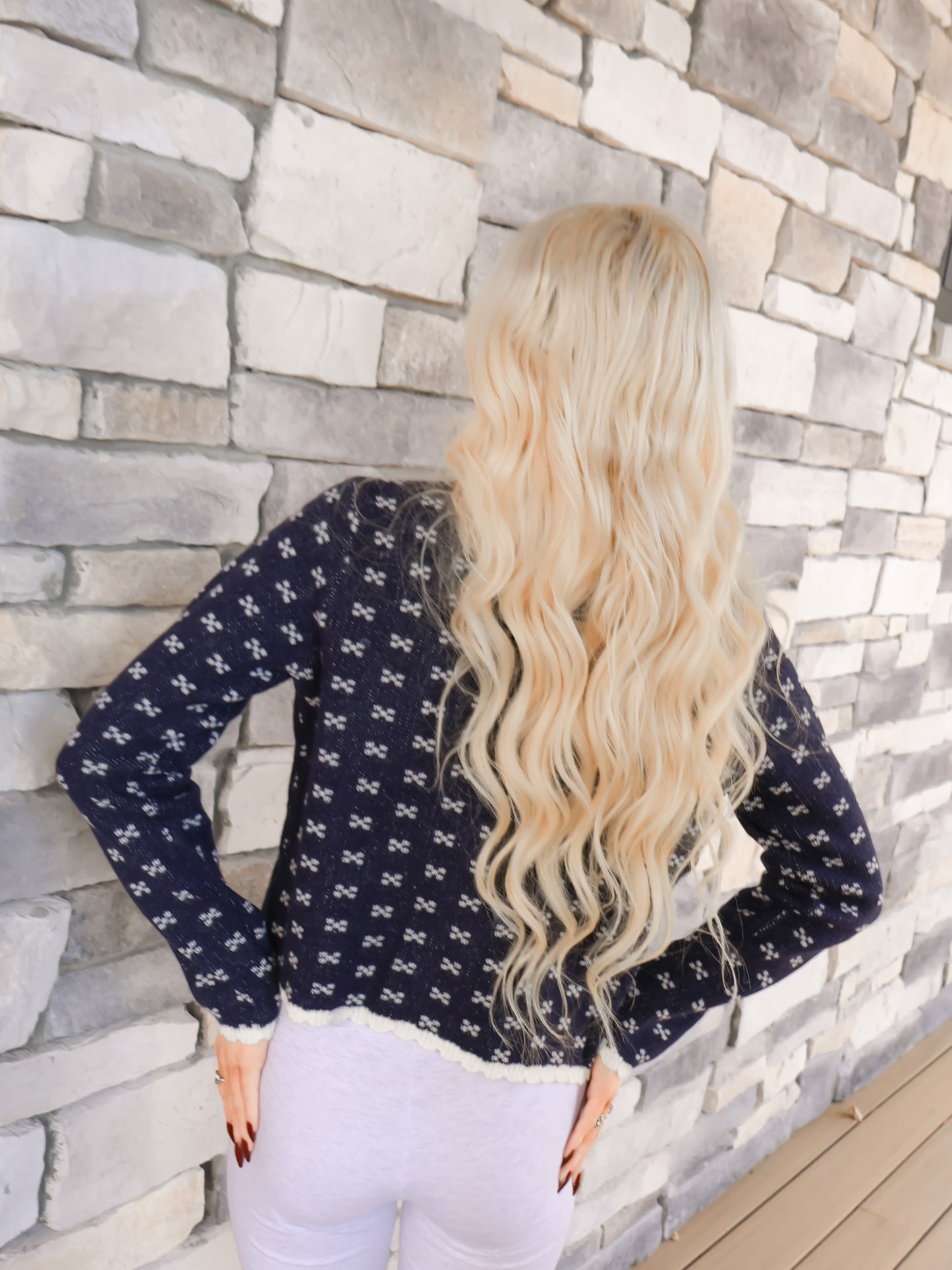 Scallop trim knit cardigan in navy blue, modeled by a woman, showing the dainty button closures.