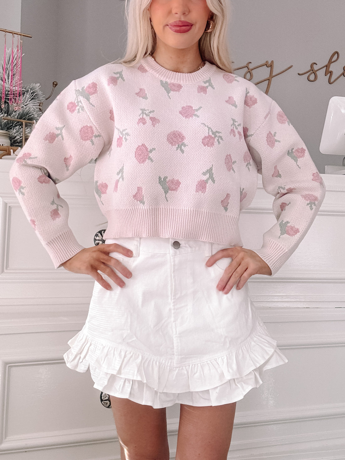 Pink floral knit cropped sweater styled with a white ruffle skirt.
