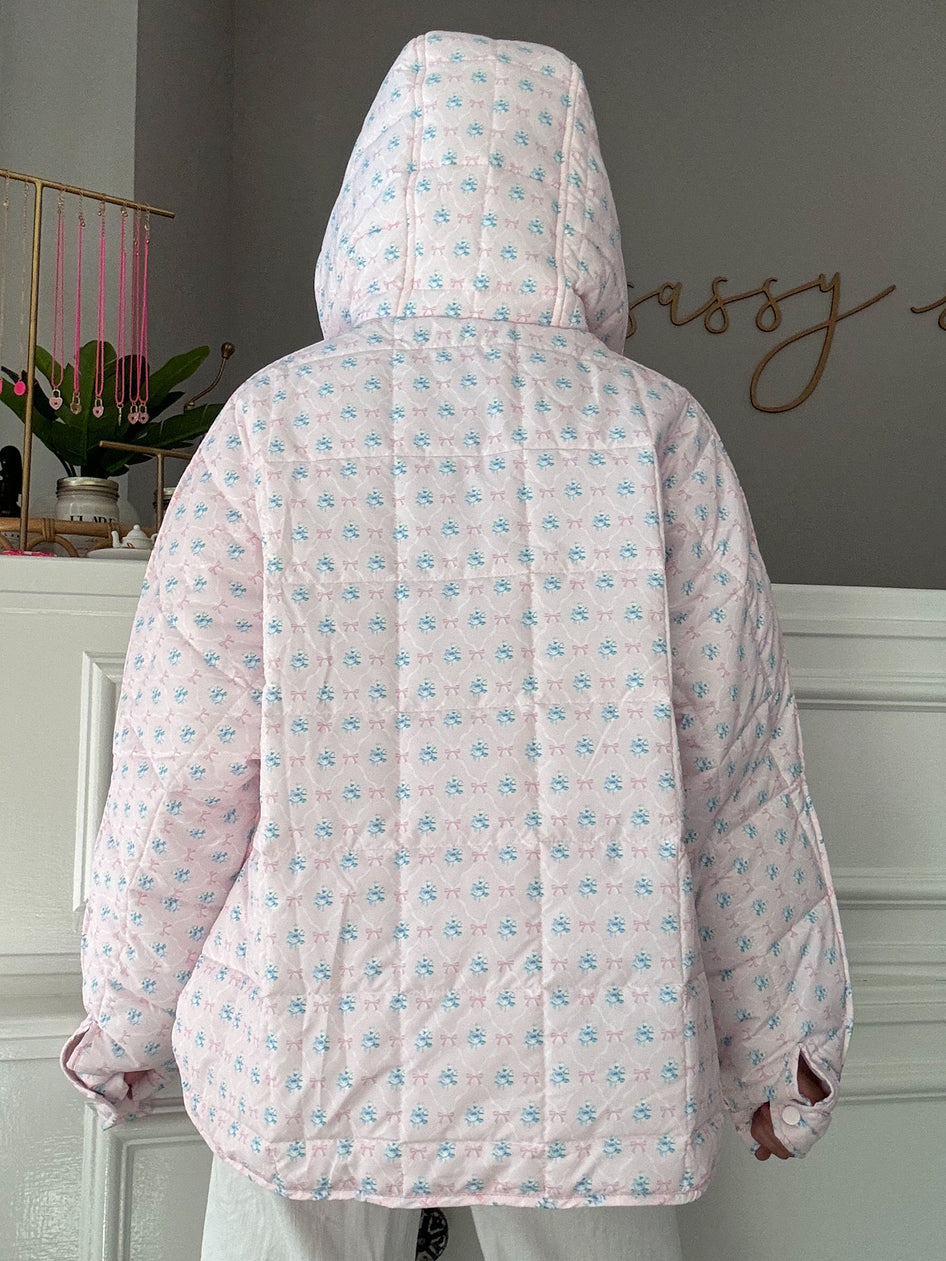 Pink quilted pullover with a floral bow print, shown from the back.
