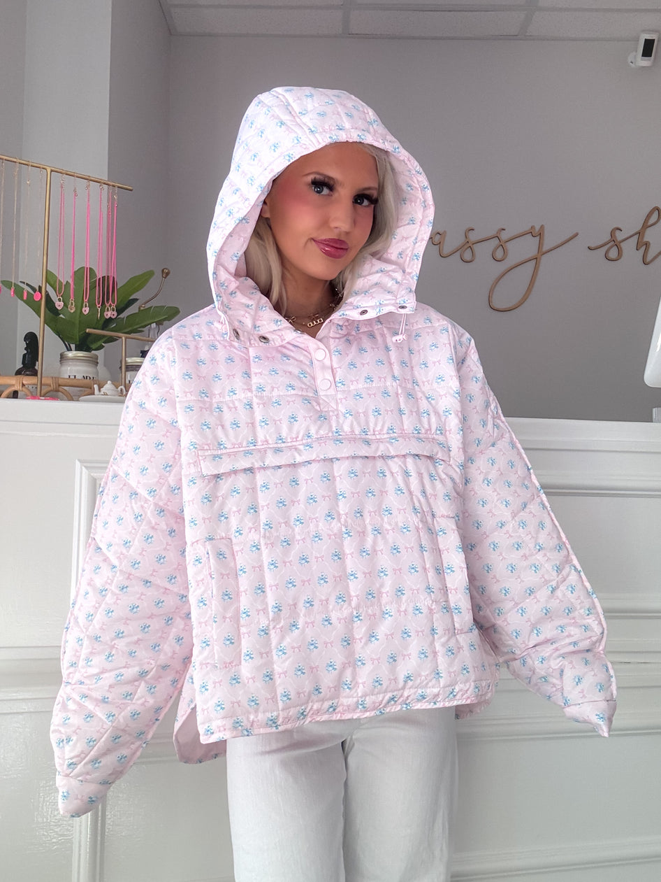 Pink quilted pullover with a floral pattern, model wearing in a boutique setting.
