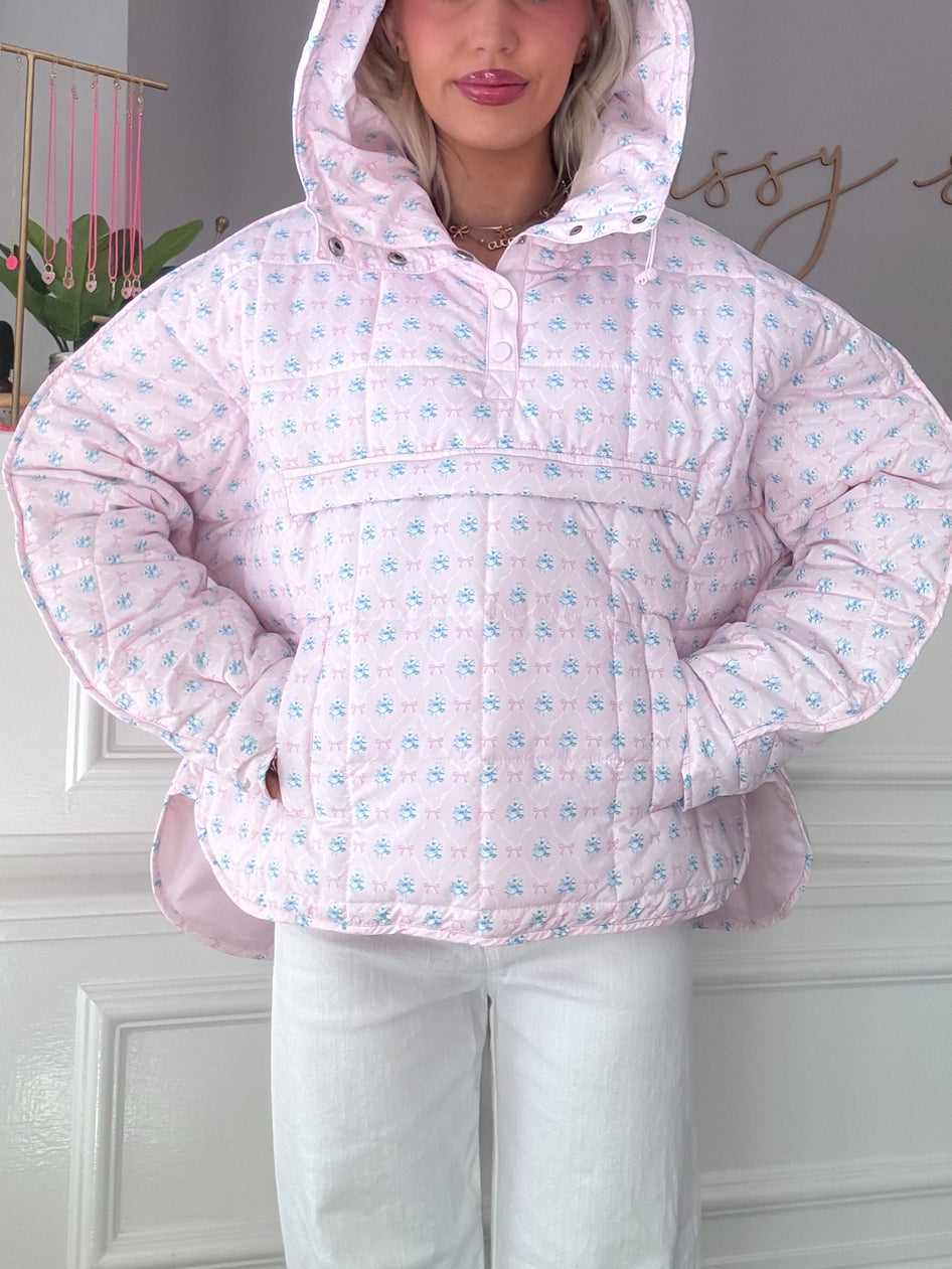 Pink quilted pullover with floral print, featuring a hood and pockets.
