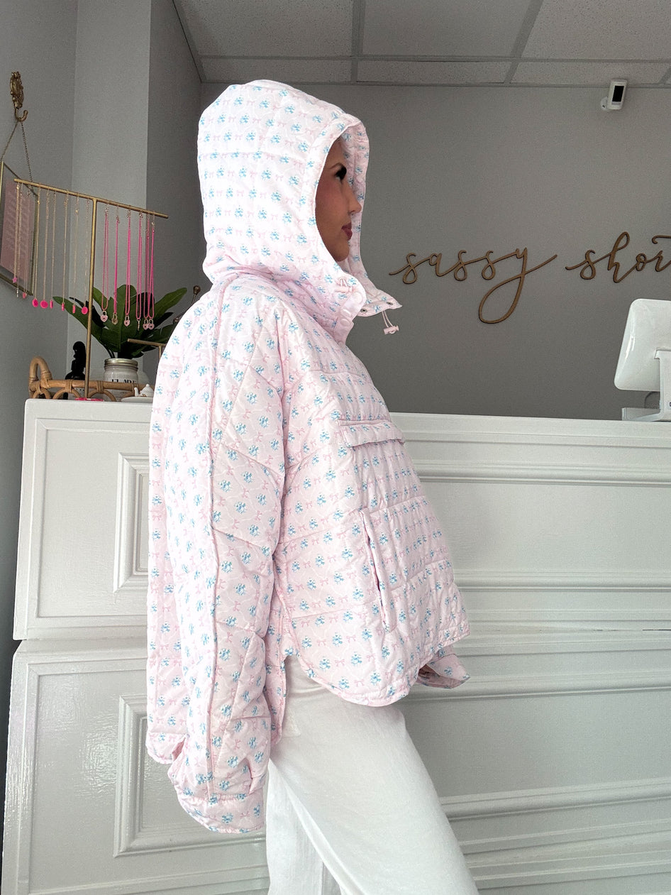 Pink quilted pullover with a floral print and a hood, shown on a model.
