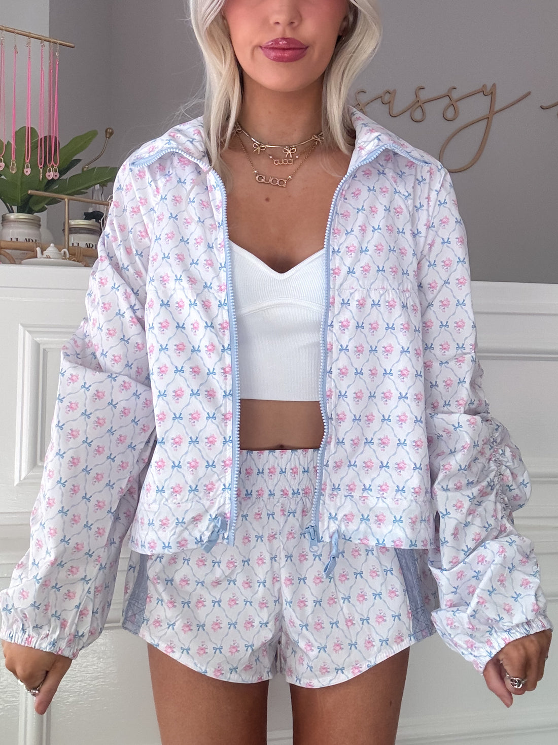White windbreaker with light blue floral print and matching shorts; model wears it with a white crop top.
