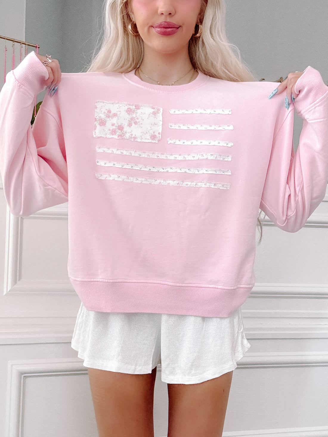 Close-up of American flag patchwork on pink crewneck, feminine patriotic outfit detail