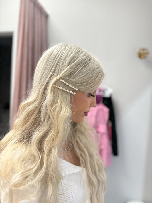 Elegant pearl and rhinestone hair clips in blonde hair.