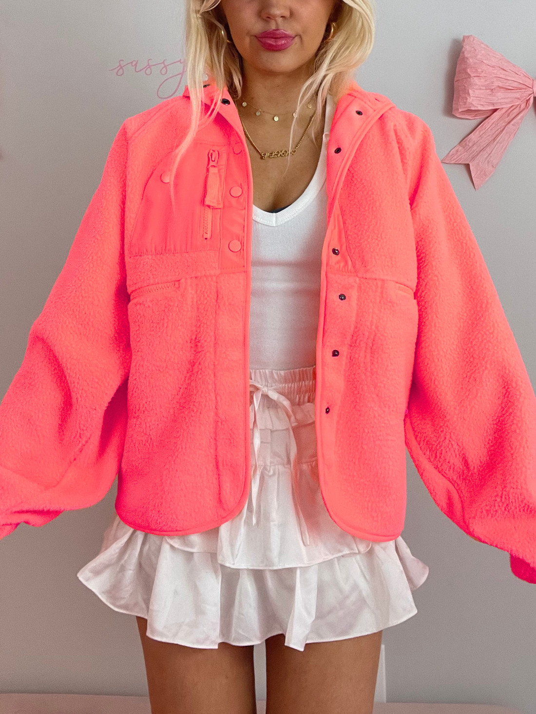 Bright pink fleece jacket with snap buttons, shown worn outdoors.