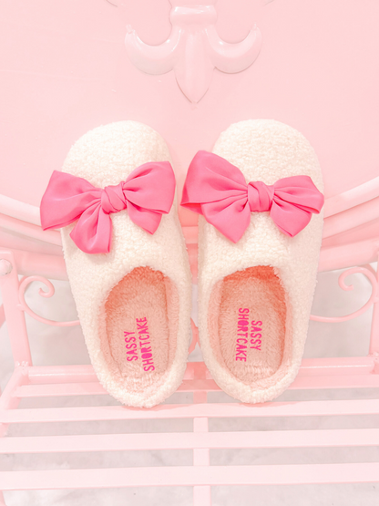 Satin Pink Bow Slippers from Sassy Shortcake – fuzzy white slippers with satin pink bows on pink background