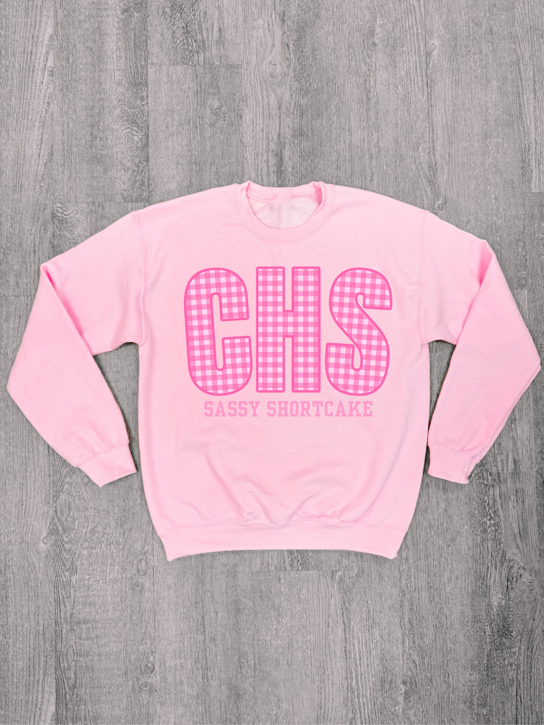 Pink CHARLESTON sweatshirt with and SASSY SHORTAKE text on a wooden surface - preppy merch 