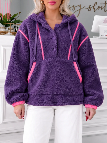 Model wearing the Sassy Shortcake Plum Pretty Pullover, a purple sherpa fleece hoodie with hot pink trim, front pocket and white pants.