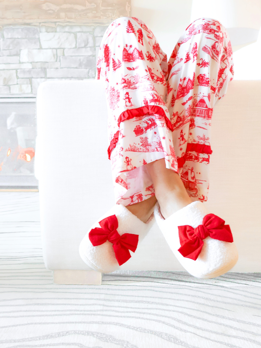 Red Bow Slippers by Sassy Shortcake on feet with holiday PJs, cozy ivory plush and bold red bows