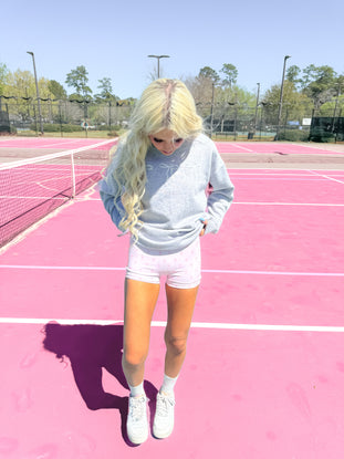Pink biker shorts with bow print, worn outdoors on a tennis court.
