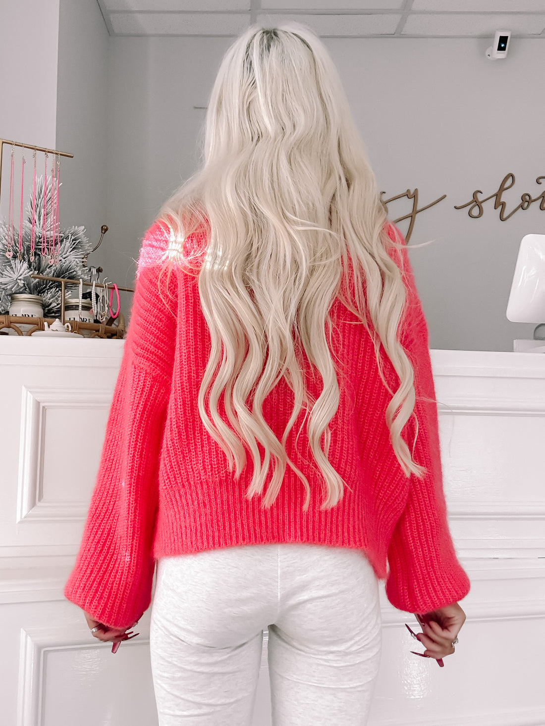 Hot pink knit sweater with balloon sleeves, shown from the back in a bright interior.
