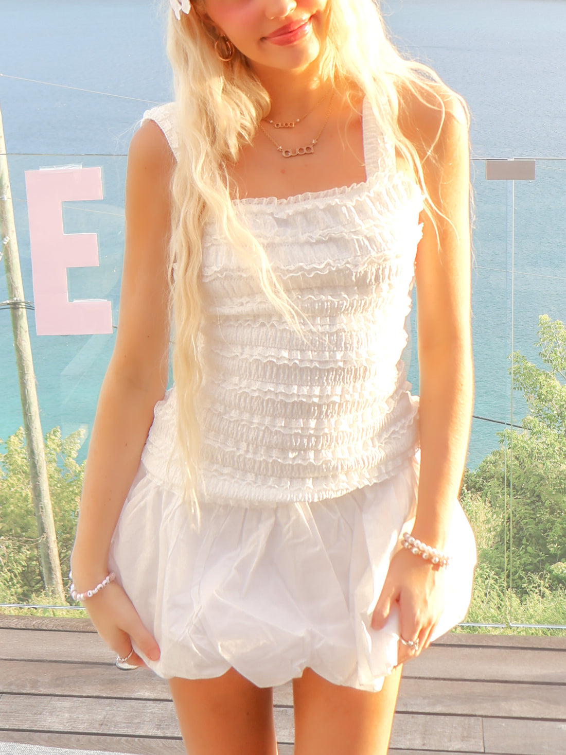 model wearing white ruffle beach infront of the ocean