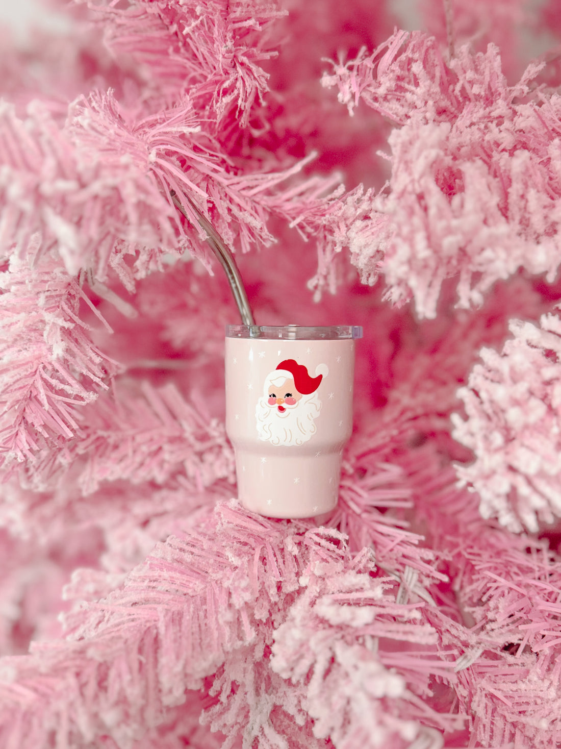 Pink Santa tumbler with straw nestled in a fluffy pink Christmas tree.
