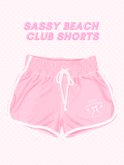 A flat lay view of the bright pink terry cloth Sassy Beach Club Shorts from Sassy Shortcake, showcasing the soft fabric texture and casual, preppy design