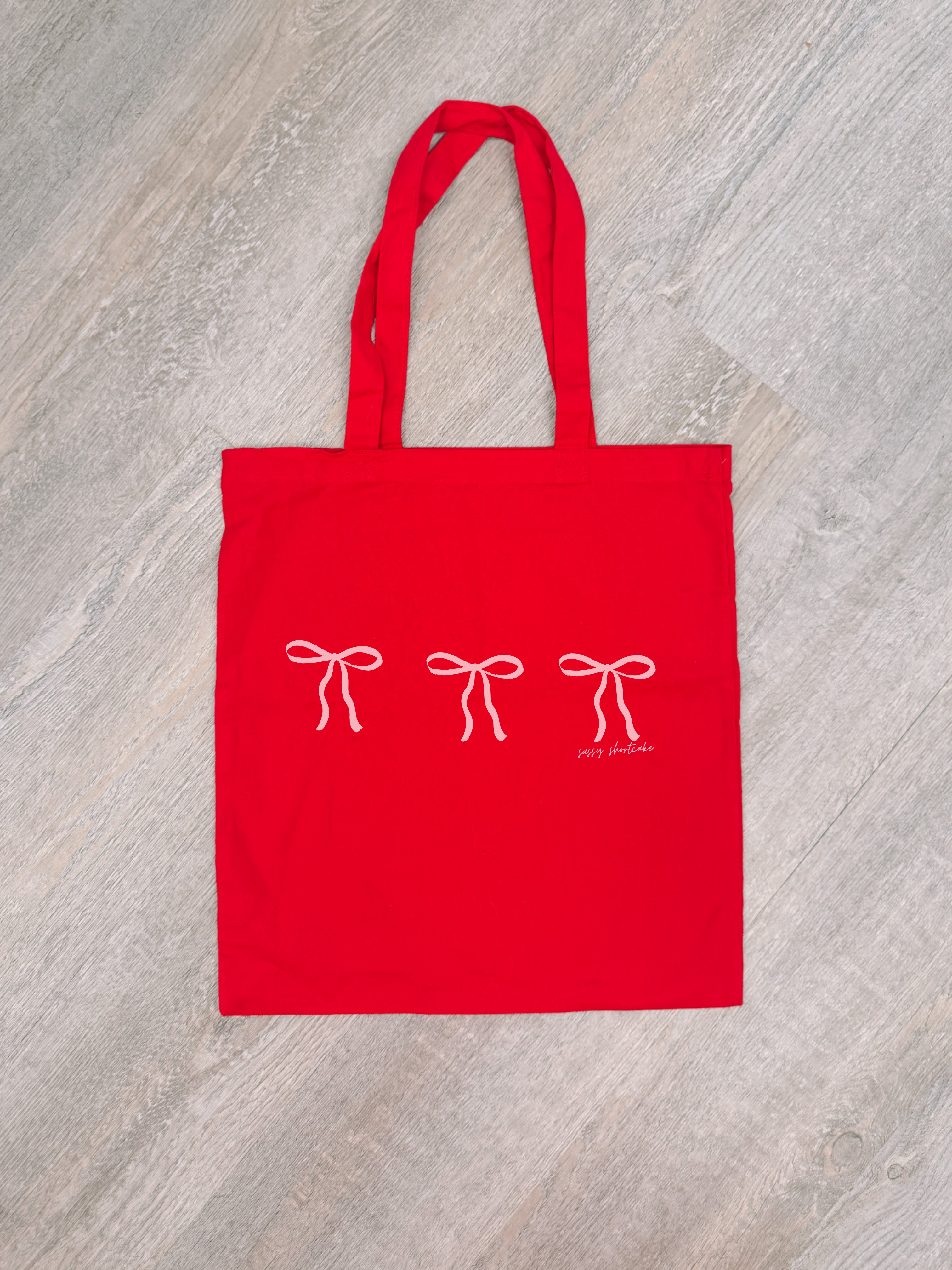 Red cotton tote bag with three pink bows and 